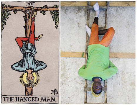 L'image est en 2 parties. A gauche, la carte de tarot du pendu, à droite, la photo d'un haïtien mimant la même scène que celle figurant sur la carte